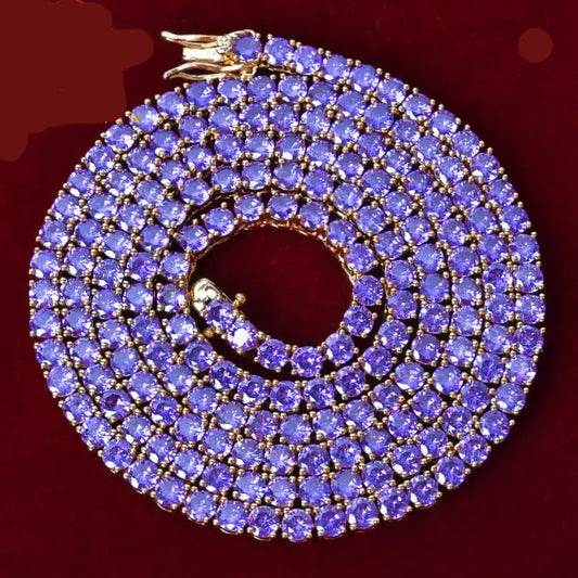 A gold-plated 5-stone chain necklace paved with round purple-blue tanzanite gemstones, coiled on a dark red background.