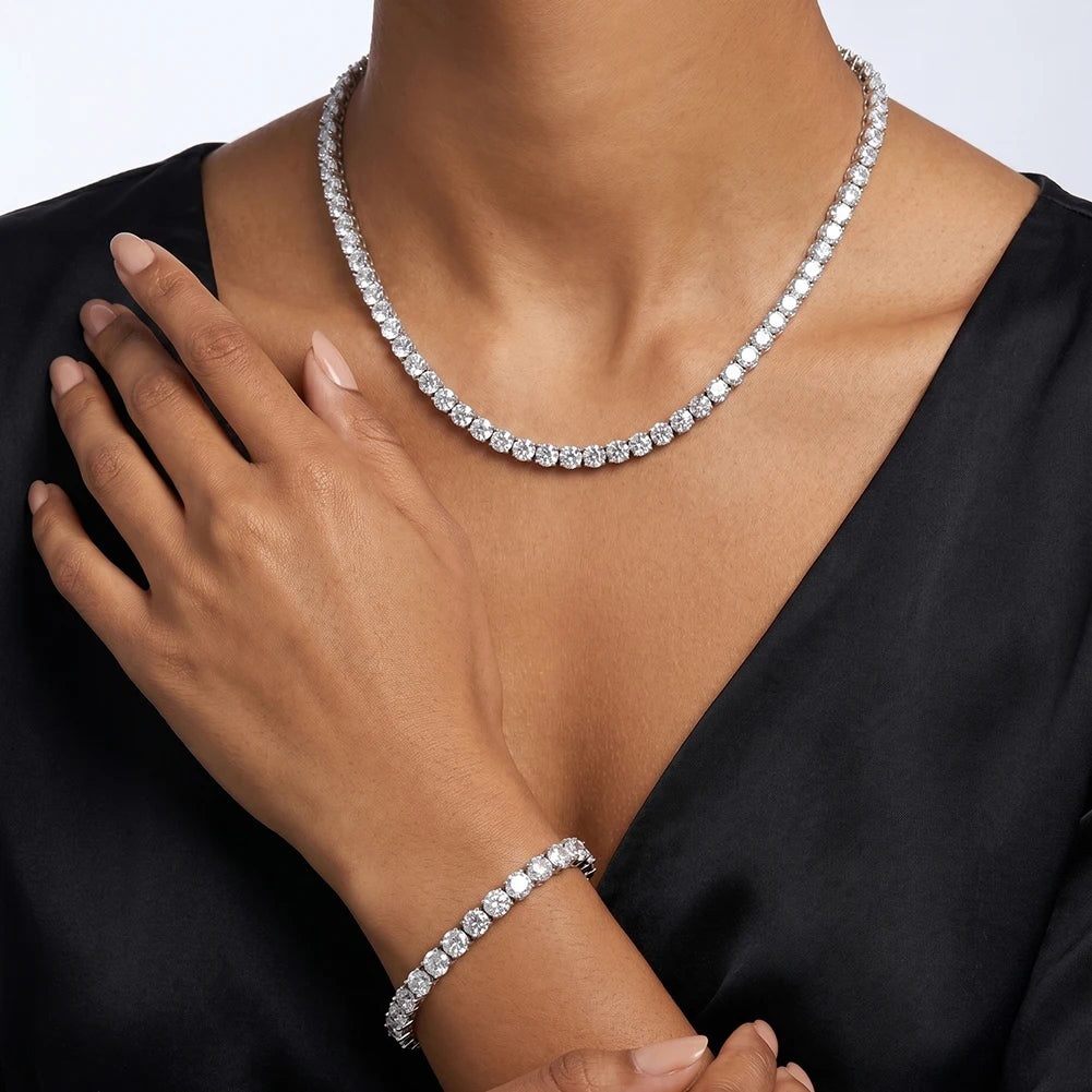 A close-up of a model wearing a sparkling silver tennis necklace and matching bracelet,top against a clean white background.
