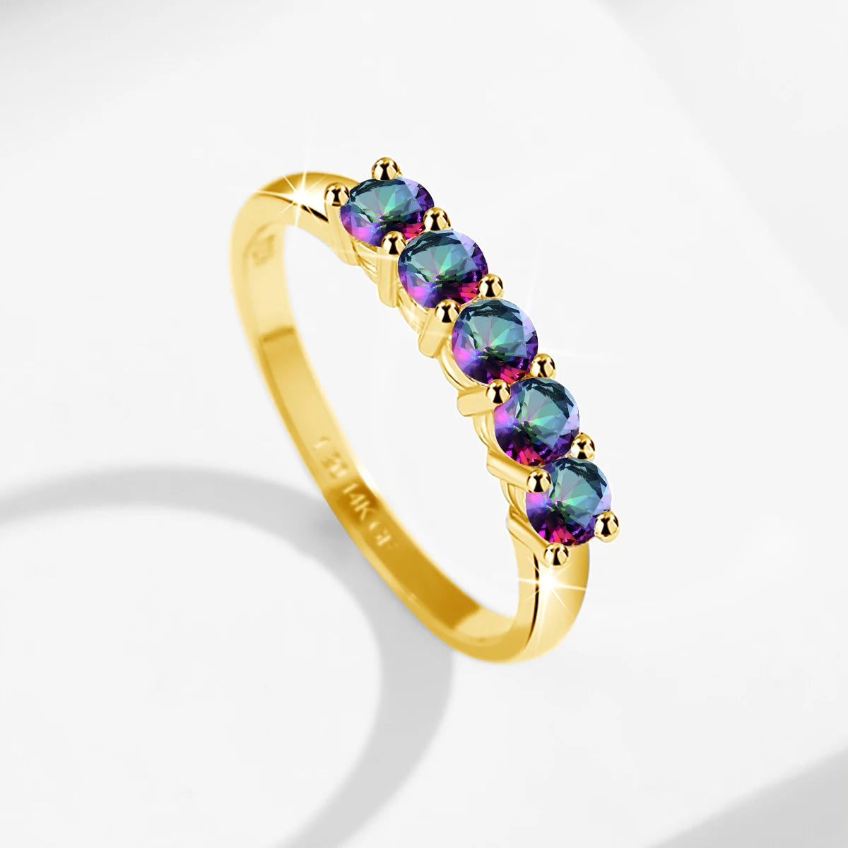 Gold ring with multicolored gemstones on a light gray background