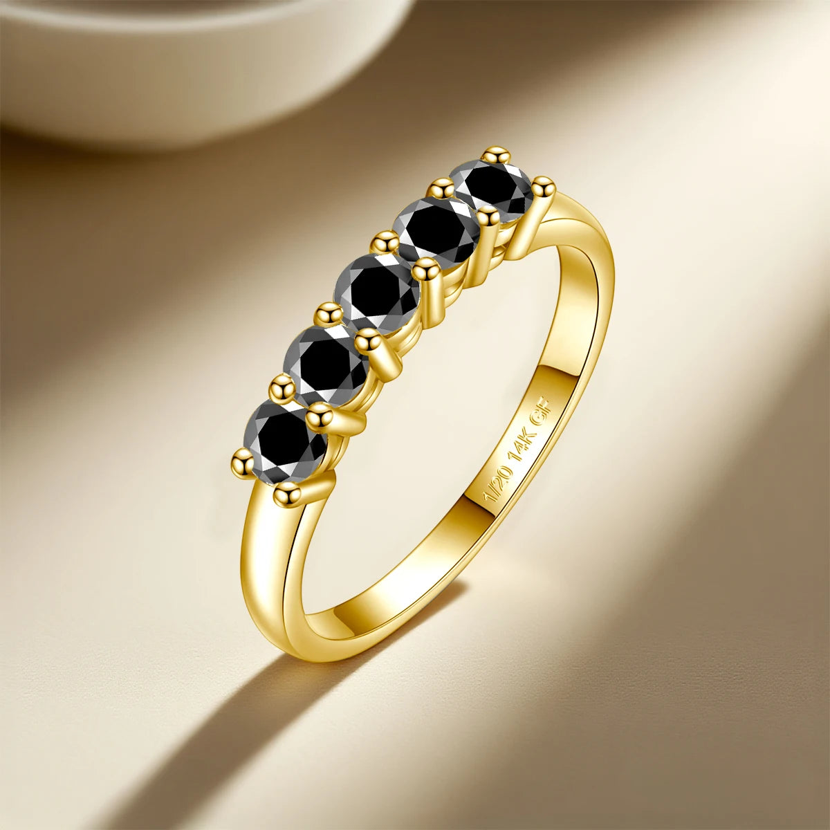 Gold ring with black gemstones on a beige background